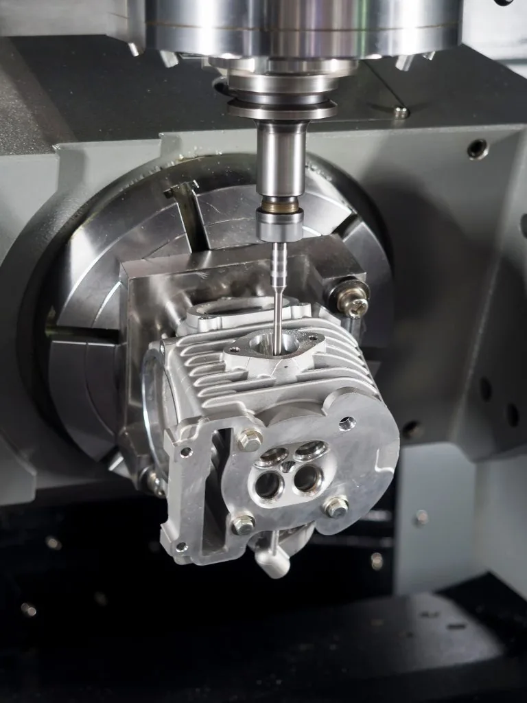 CNC machining center milling an aluminum part held in a vise